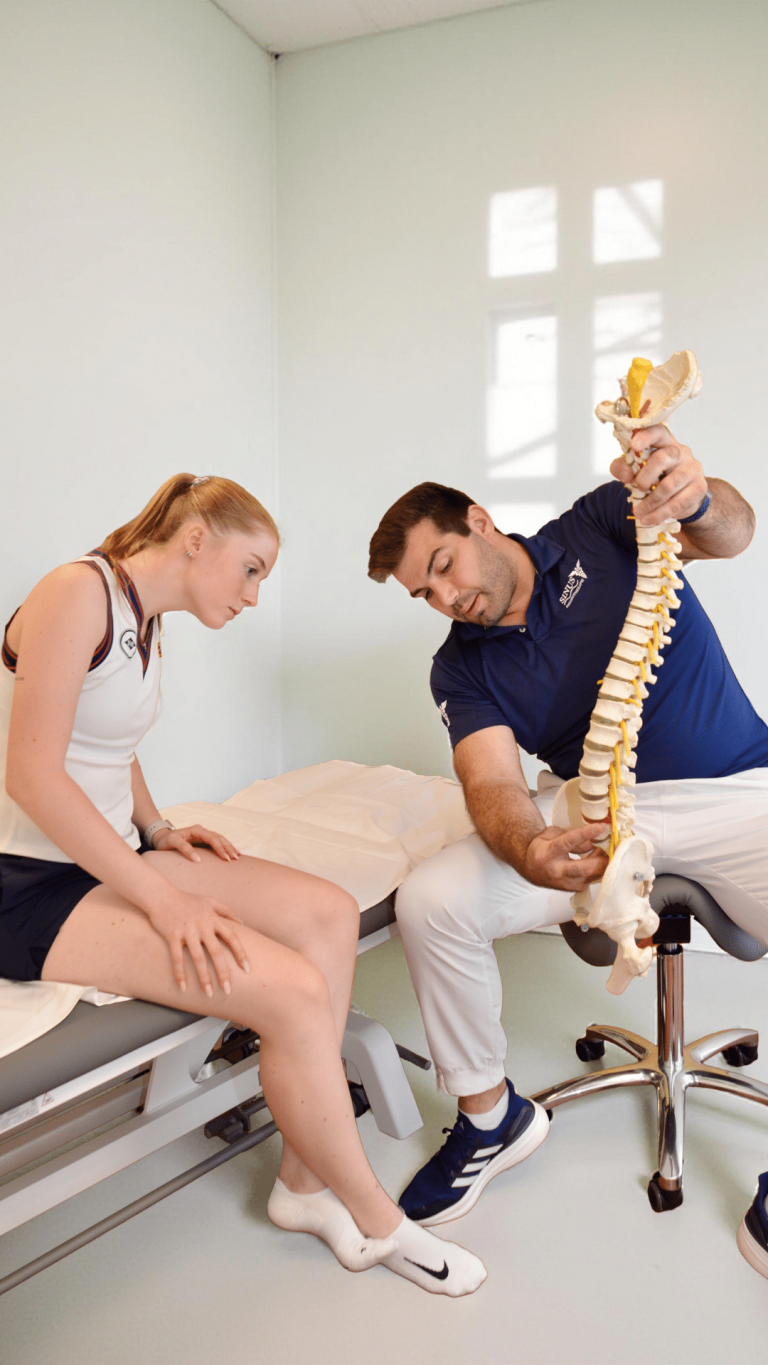 Physiotherapeut erklärt Patientin die Wirbelsäule anhand eines Anatomiemodells in Hamburg