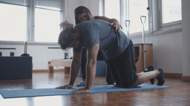 Physiotherapeutin unterstützt Patient beim Rückentraining auf Matte in Hamburg
