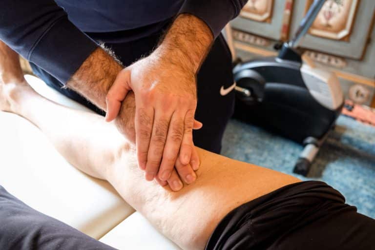 Mobiler Physiotherapeut aus Hamburg behandelt den Oberschenkel eines Patienten mit manuellen Grifftechniken