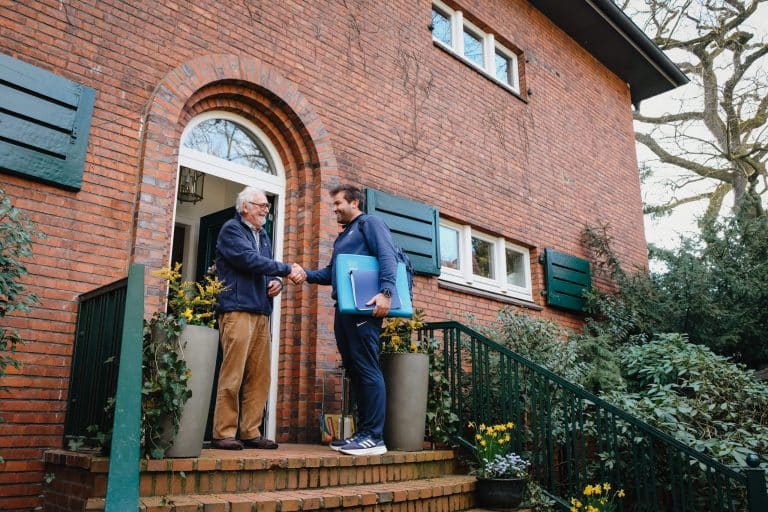 Mobiler Physiotherapeut aus Hamburg trifft einen Patienten vor einem Wohnhaus zum Hausbesuch
